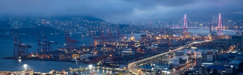 Cloudy skies gather over shipping containers and gantry cranes illuminated at night at the Port of Busan in South Korea. Photographer: SeongJoon Cho/Bloomberg