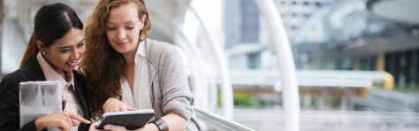 An image of two professional woman talking and looking at a tablet