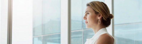 An image of a businesswoman standing in her office looking out the window