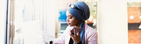 Asian Muslim woman with blue headscarf / hijab on the phone. Professional small business owner working in office.